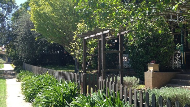 A garden with a wooden pergola, a pathway, and various plants.