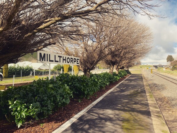A road sign for 'MILLTHORPE' with a pathway lined by trees and shrubs.