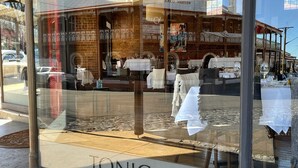 A restaurant with a brick facade, outdoor seating, and a clear view of the interior through the window.