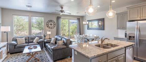 A modern kitchen with granite countertops, stainless steel appliances, and a dining area with a table and chairs.