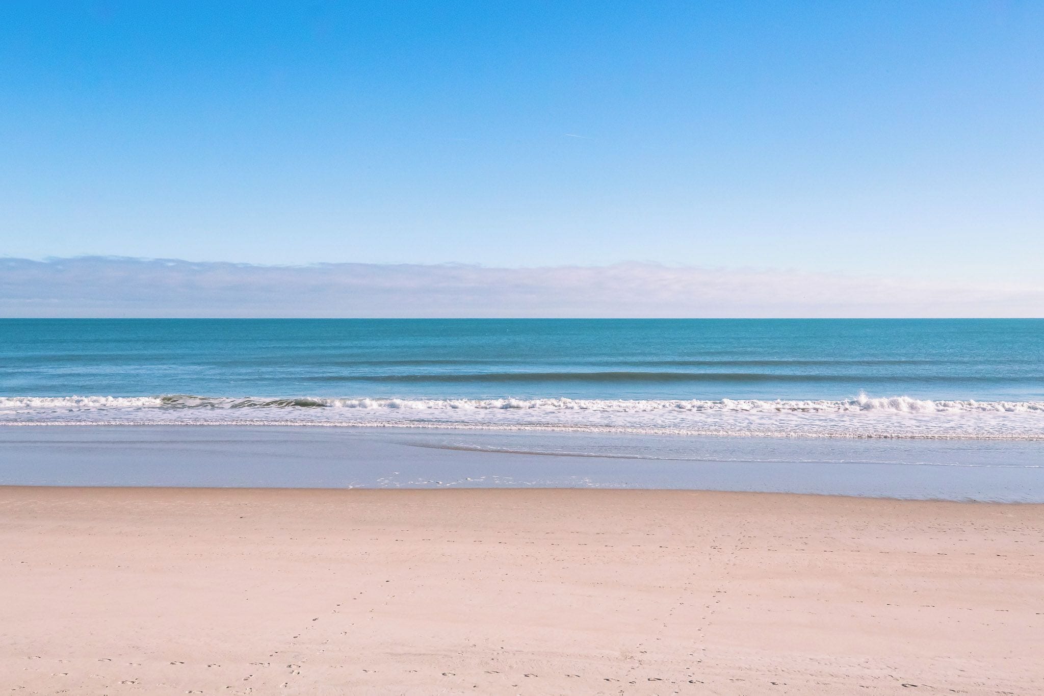 Una playa con cielo despejado y mar tranquilo.