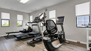 A gym with treadmills, an elliptical, and a stationary bike. - Shell Shocked - Oceanfront Surf Condo, Sleeps 6 (Surf City)