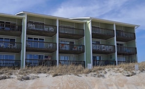 Un hôtel à plusieurs étages, doté de balcons, situé sur une plage de sable.