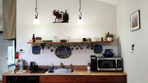 Una cocina con microondas, lavamanos y platos decorativos en la pared.