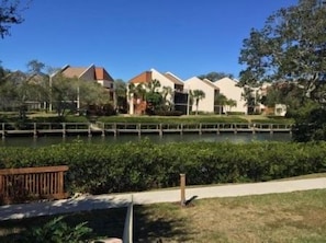 A waterfront property with a dock, a grassy area, and buildings with a uniform architectural style.