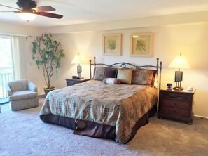 A bedroom with a bed, nightstands, a chair, and a ceiling fan.