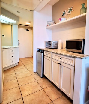 Cozinha equipada com micro-ondas, torradeira e uma estante com objetos decorativos.