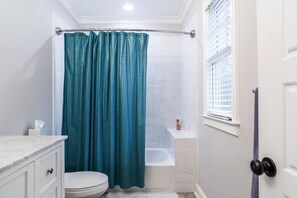 A bathroom with a toilet, a bathtub, and a shower curtain. - Heart of Midtown - Walkable - Private Pet Relief Yard - Gated Parking (Atlanta)