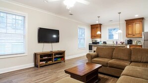 Una sala de estar con sofá, mesa de centro, televisor y aparador de madera.