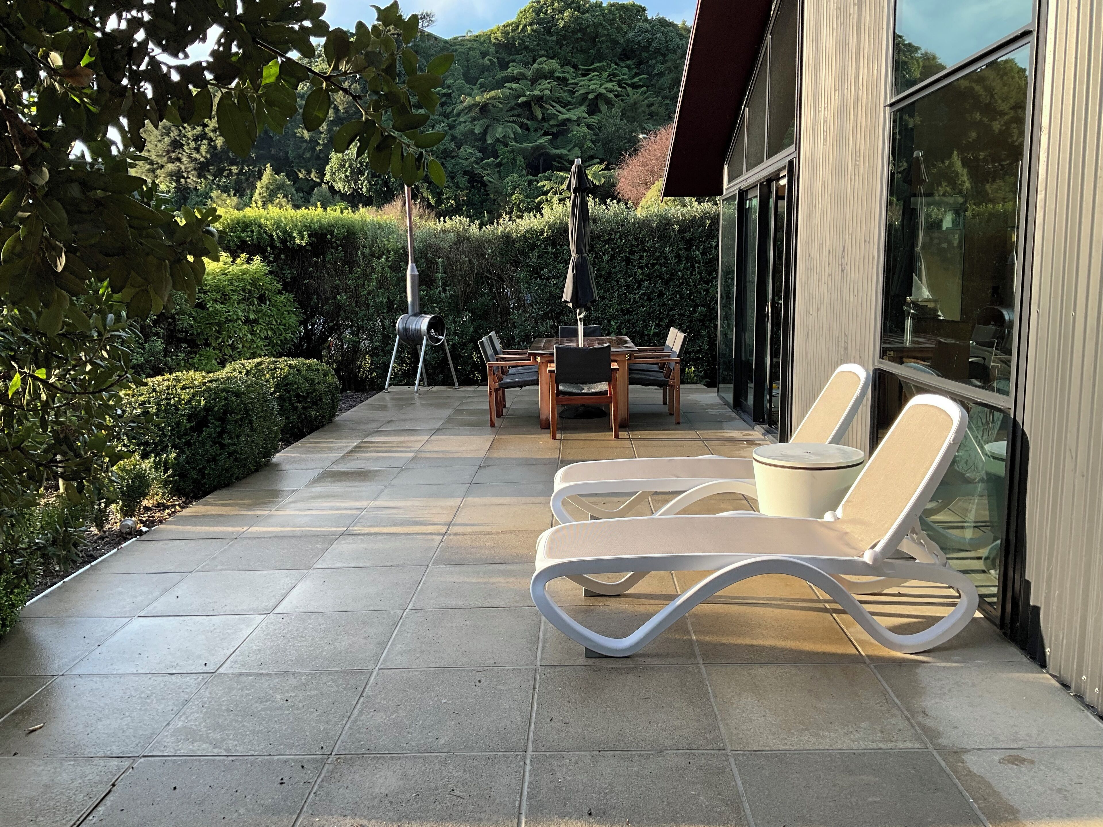An outdoor patio with a table and chairs, a grill, and a glass wall.