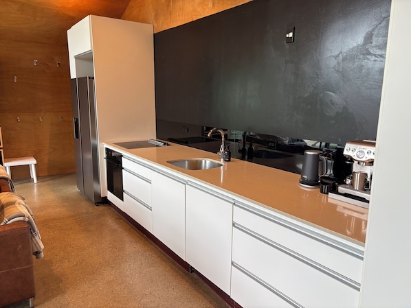 Eine moderne Küche mit einem Edelstahlkühlschrank, einer Spüle und einer Kaffeemaschine.