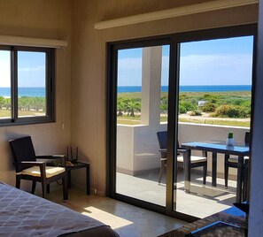 Ein Balkon mit Blick auf den Ozean, ein Tisch mit Stühlen und ein Bett im Zimmer.