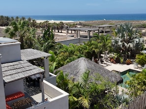 Un complex turístic amb piscina, zona d'estar a l'aire lliure i vista a la platja.