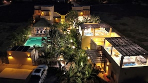 Un complex turístic amb piscina, diverses habitacions i un cotxe aparcat a l'exterior.