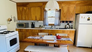Une cuisine avec des meubles de rangement en bois, une cuisinière, un four à micro-ondes et un réfrigérateur.