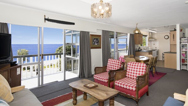 A living room with a view of the sea, a dining area, and a kitchen. - Maple's Den - Collingwood beach house (Collingwood)