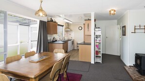 A compact living space with a dining area, kitchenette, and a small living room with a fireplace. - Maple's Den - Collingwood beach house (Collingwood)