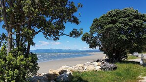 A coastal landscape with a beach, rocky outcrops, and trees. - Maple's Den - Collingwood beach house (Collingwood)