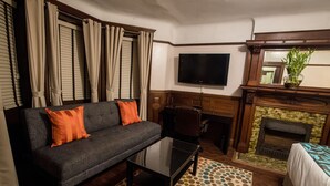 Un salon comprenant un canapé, une table basse, un téléviseur à écran plat, une cheminée et un tapis à motifs.