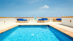 Una piscina con baldosas azules y vistas al mar.