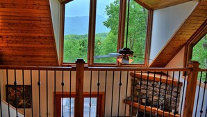Ein Zimmer mit einem großen Oberlicht, Holzbalken, einem Deckenventilator und Blick auf Grünfläche.