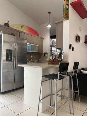 A modern kitchen with stainless steel appliances, a central island with bar stools, and a microwave above the sink.