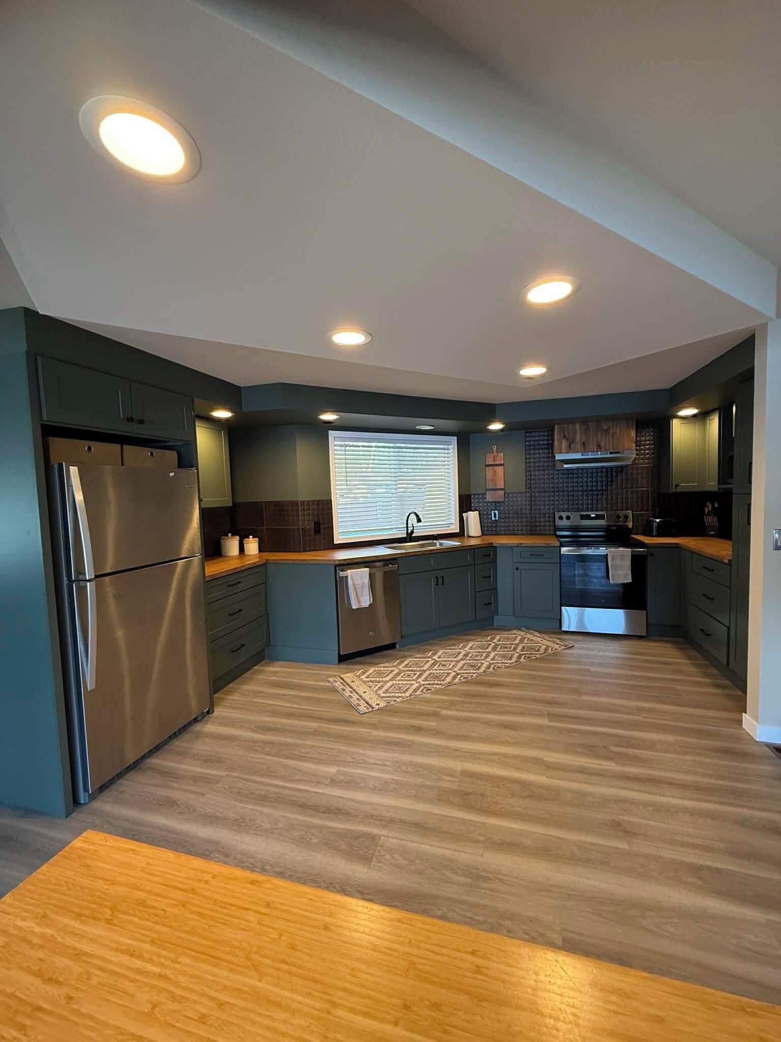 Una cocina moderna con electrodomésticos integrados, una isla central e iluminación empotrada en el techo.