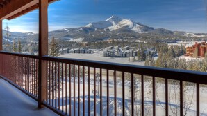 A snowy mountain landscape with a view of a resort area and buildings in the background.