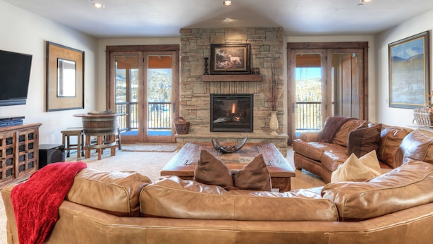 A spacious living room with a stone fireplace, leather sofas, and a flat-screen TV.