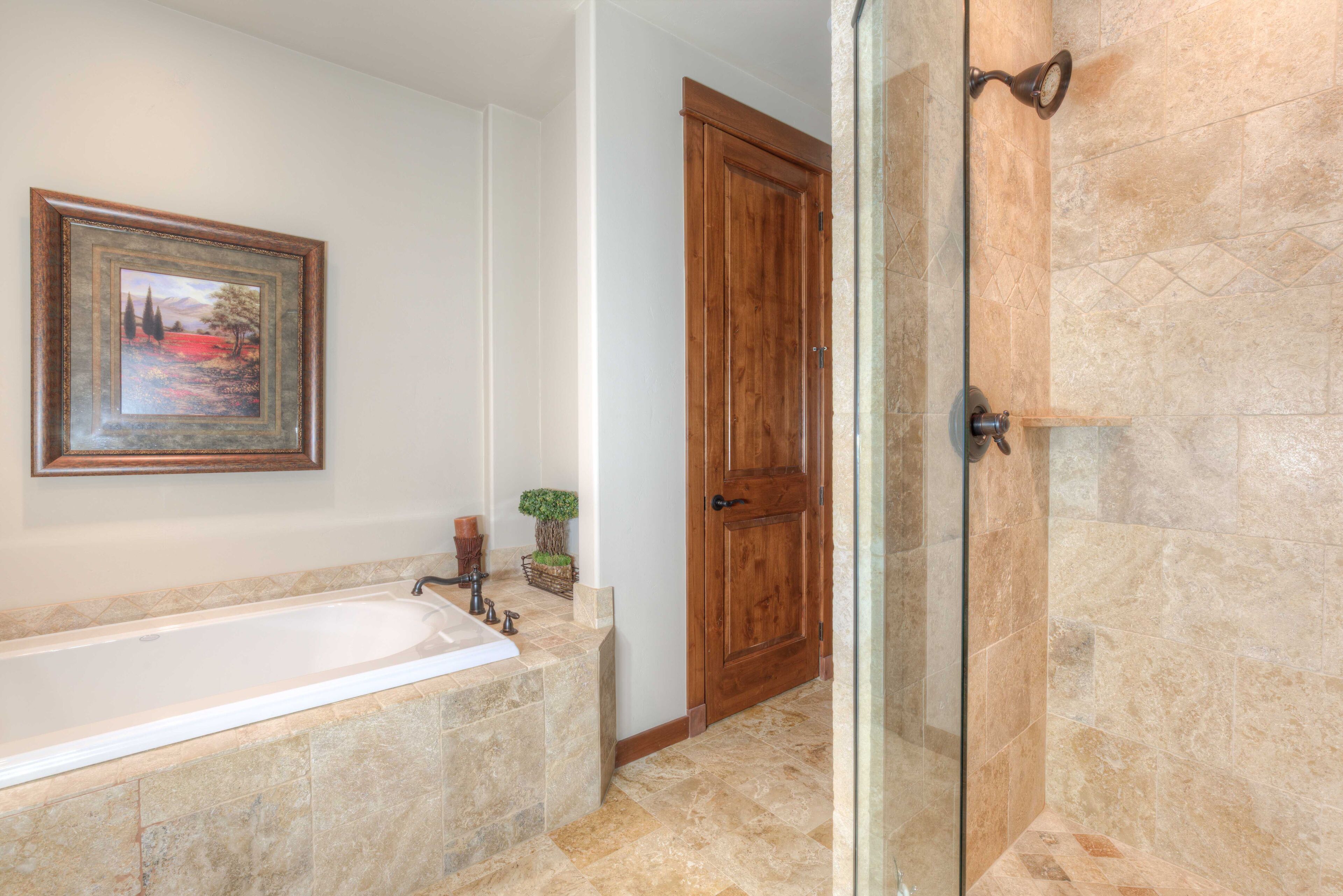 A bathroom with a bathtub, a wooden door, and a shower area.