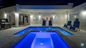Un espace piscine extérieur moderne, doté d’un jacuzzi, de chaises longues et d’un barbecue.
