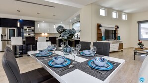Un espace repas moderne avec une table blanche dressée pour six personnes, entourée de chaises noires.