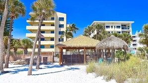 A beachside hotel with multiple-story buildings, a thatched-roof structure, and palm trees. - Steps to Siesta Key Beach! Direct Access to Private Beach, Heated Pool. Sea Shell (Siesta Key)