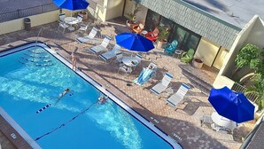 A swimming pool with lounge chairs and umbrellas, surrounded by a tiled patio area. - Steps to Siesta Key Beach! Direct Access to Private Beach, Heated Pool. Sea Shell (Siesta Key)
