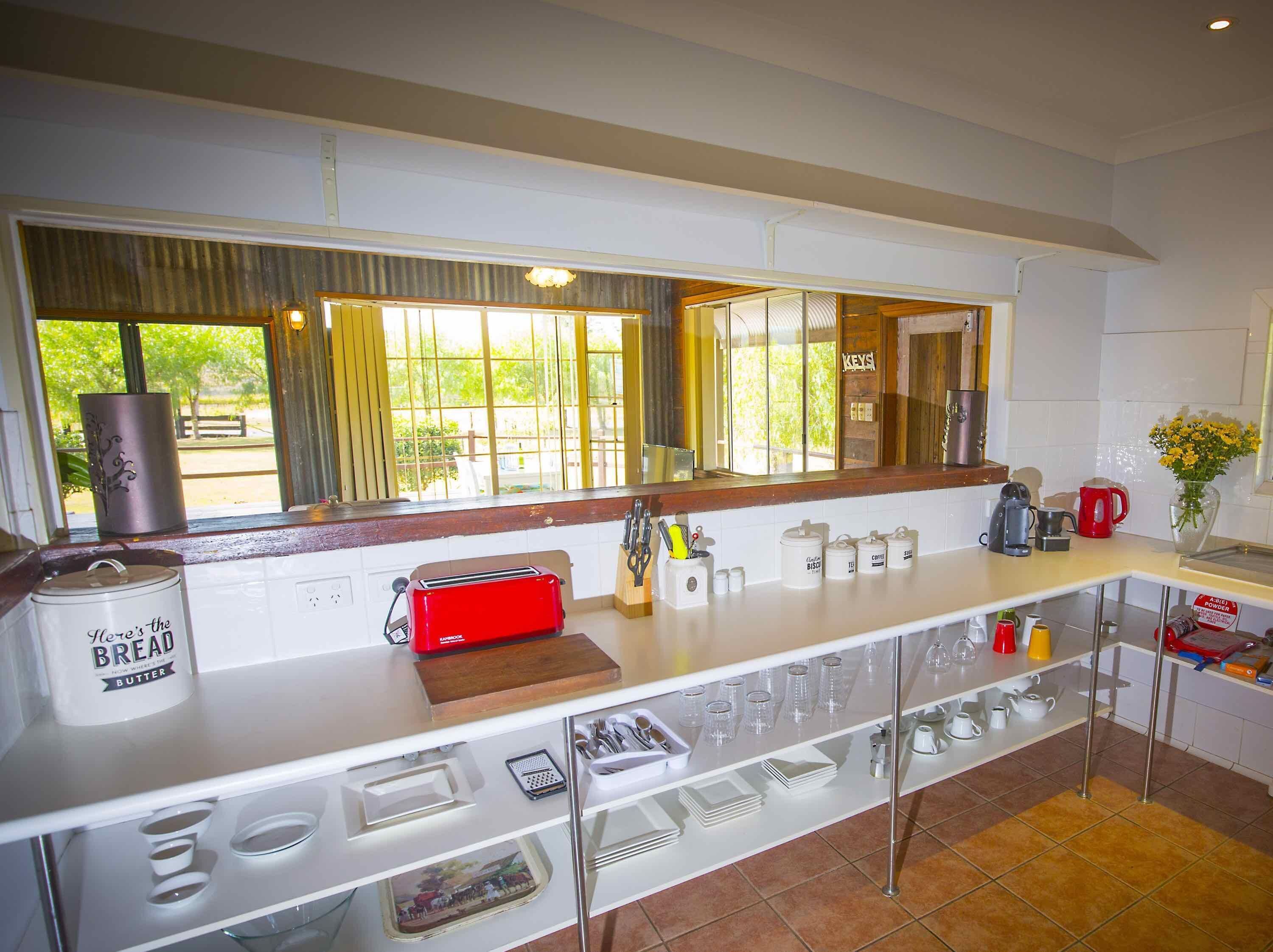 A modern kitchen with a large window, a red toaster, and various kitchen utensils on the counter.