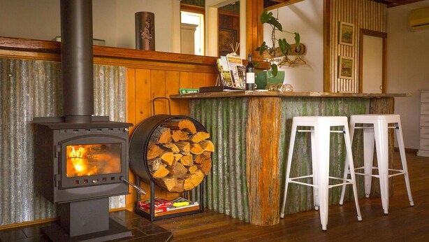 Ein gemütliches Zimmer mit Kaminofen, einer Bar mit Hockern und rustikalem Einrichtungsstil.