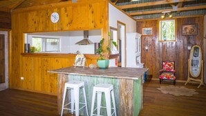 Ein rustikales Holzinterieur mit Küchenbereich, Barhocker und einem dekorativen Stuhl.