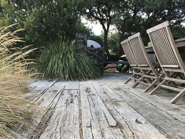 A wooden deck with chairs and a stone wall.