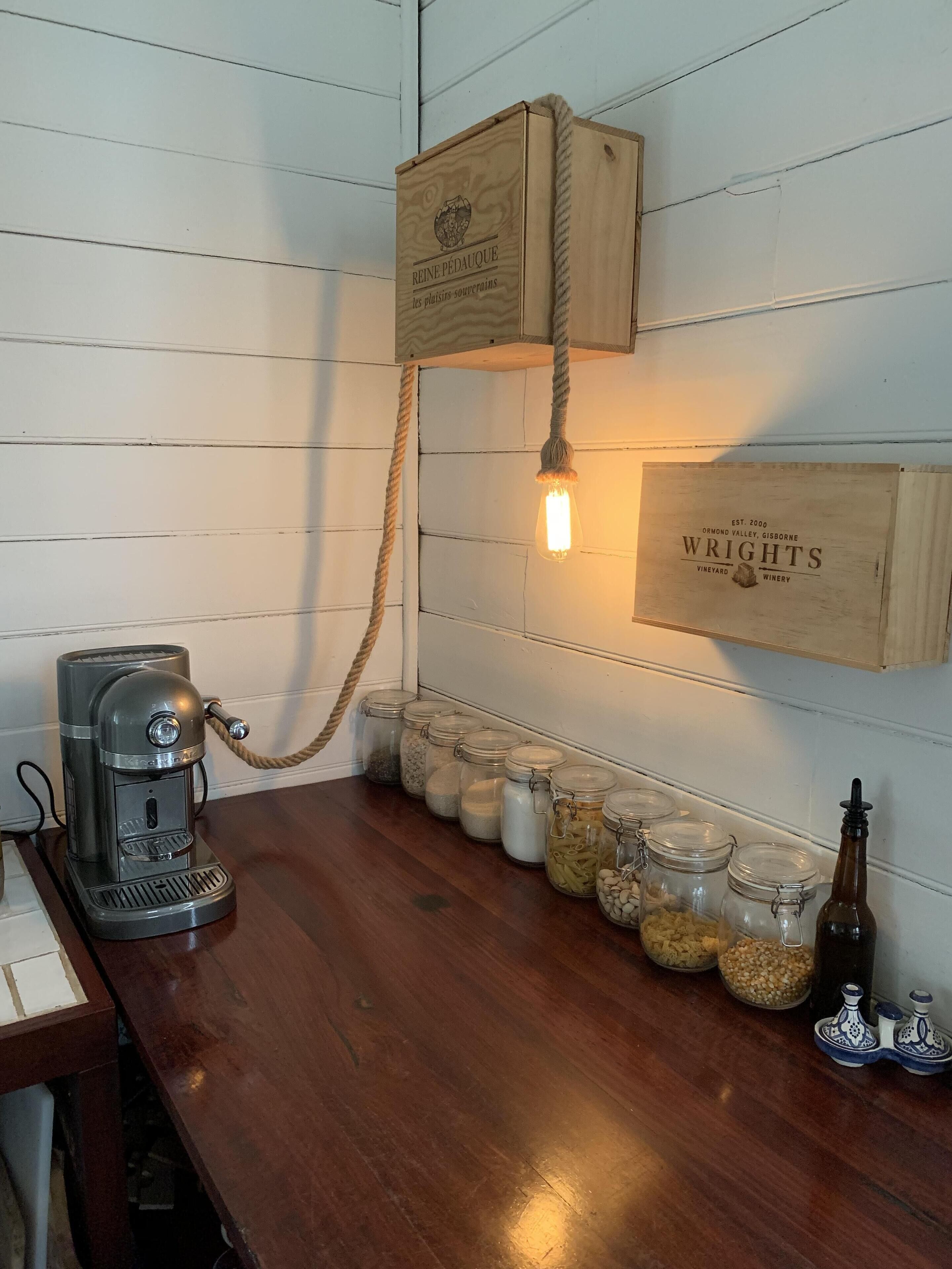 Une machine à café en bois, posée sur un comptoir en bois, avec des pots d’épices et une bouteille d’huile d’olive.