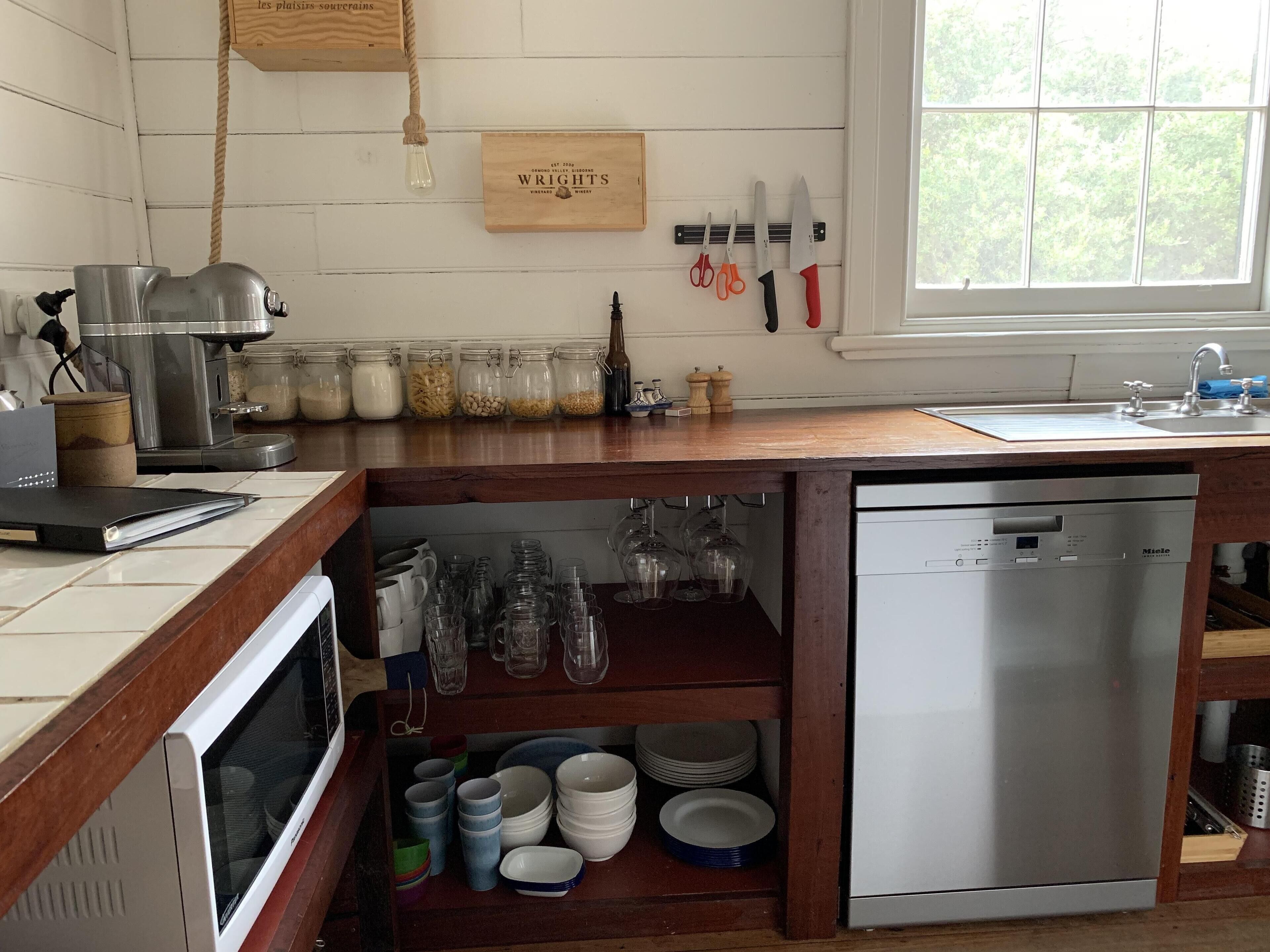 Una cucina con un piano di lavoro in legno, una macchina da caffè, barattoli di ingredienti e una lavastoviglie.