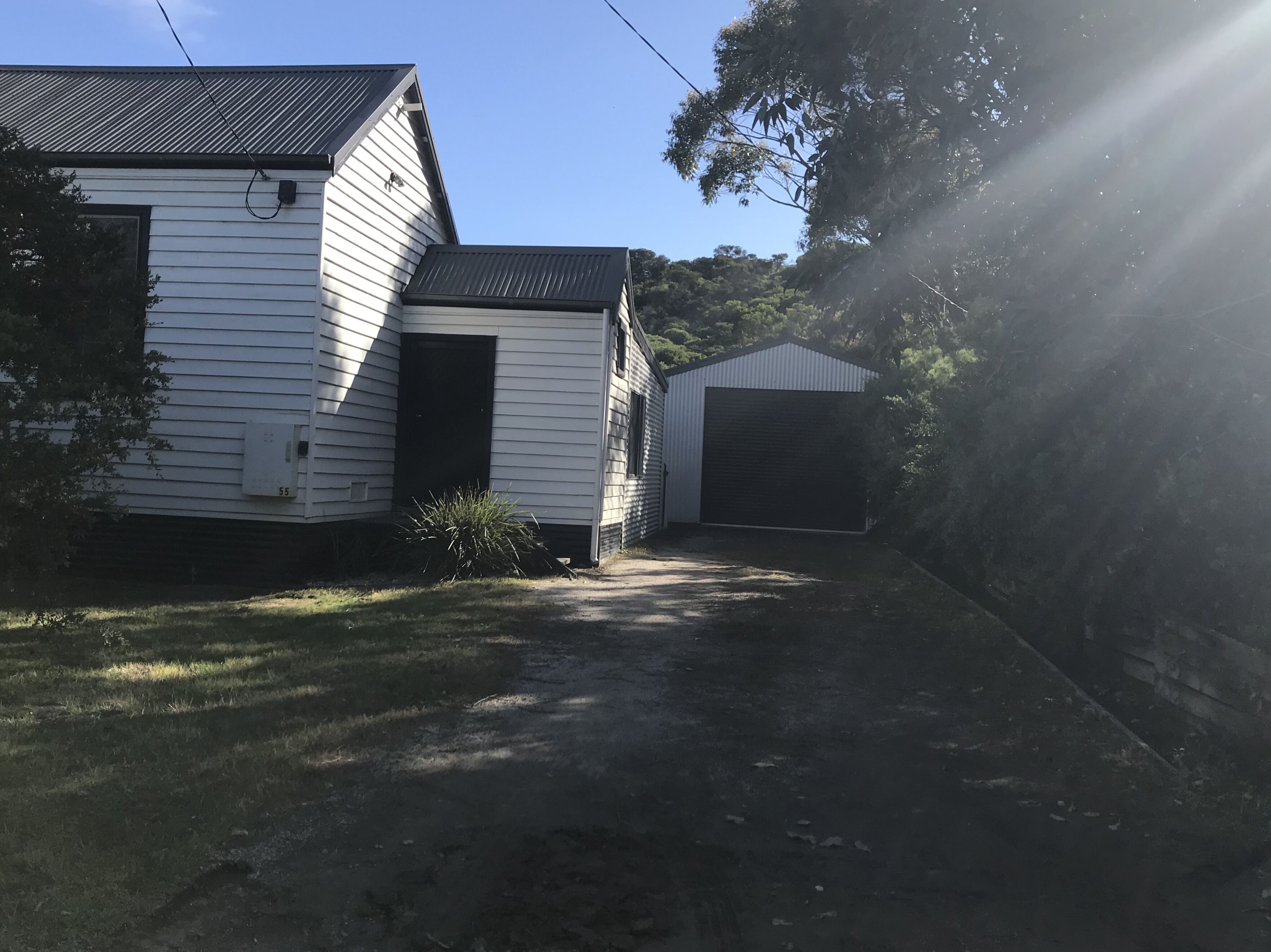 A residential property with a detached garage, a covered driveway, and a small shed.