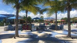 A sunny outdoor area with palm trees, benches, and colorful umbrellas.