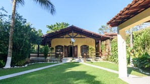 A two-story house with a tiled roof, a front porch, and a well-maintained lawn.