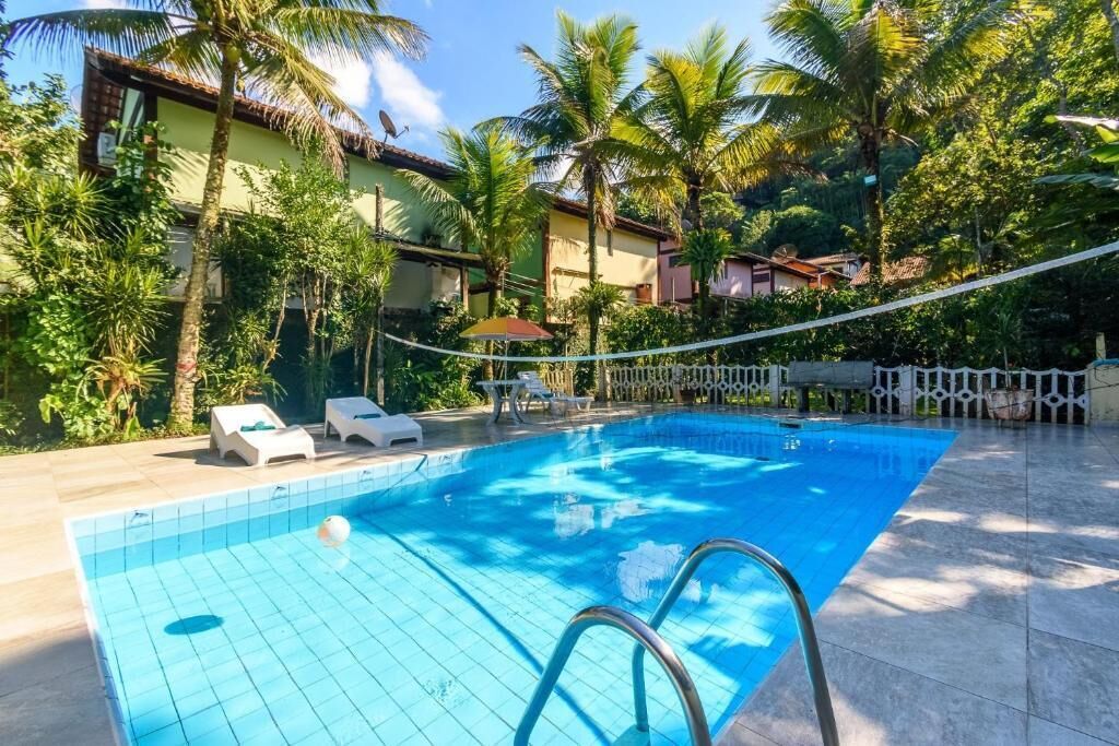 Una piscina con sillones de descanso y palmeras.