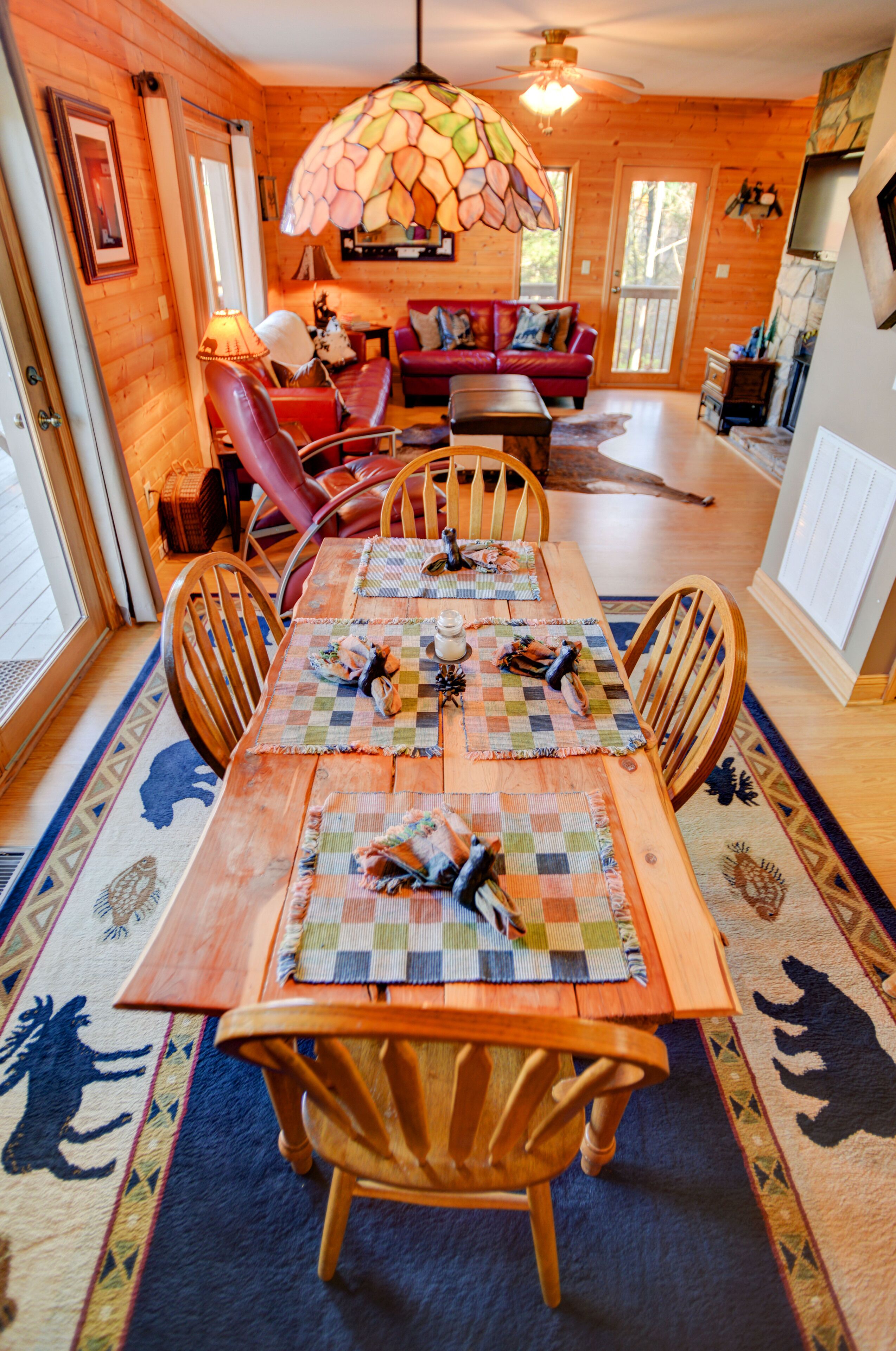 Une salle à manger en bois avec une grande table, des chaises et un plafond orné de vitraux colorés.