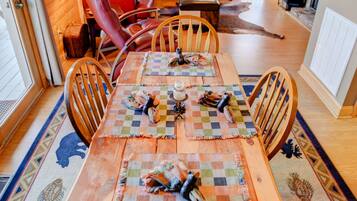 Une salle à manger en bois avec une grande table, des chaises et un plafond orné de vitraux colorés.