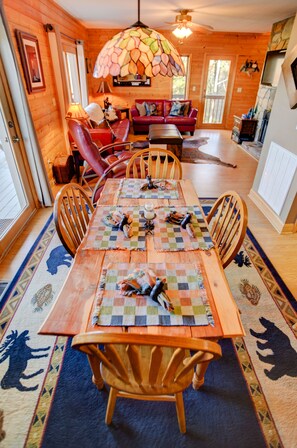 A wooden dining room with a large table, chairs, and a colorful stained glass ceiling. - Charming Cabin Near Boone - Picturesque Views - NEW Hot Tub & Hiking Trails (Ferguson)