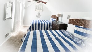 Ein Schlafzimmer mit zwei Betten, einem Deckenventilator, einem Schminktisch und einem Fenster mit Vorhängen.