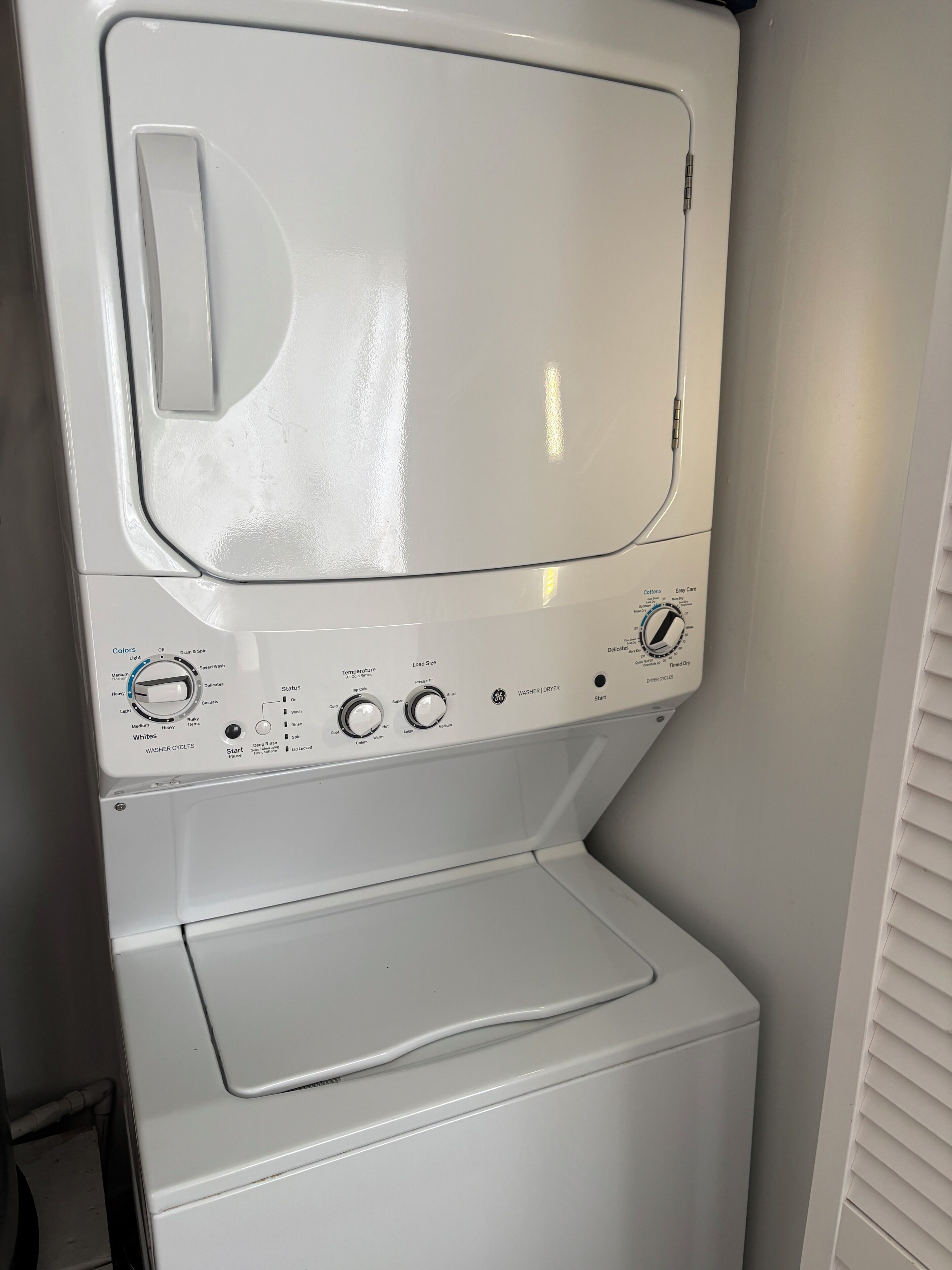 A front view of a white washing machine with control panel, water level indicator, and a detergent drawer.