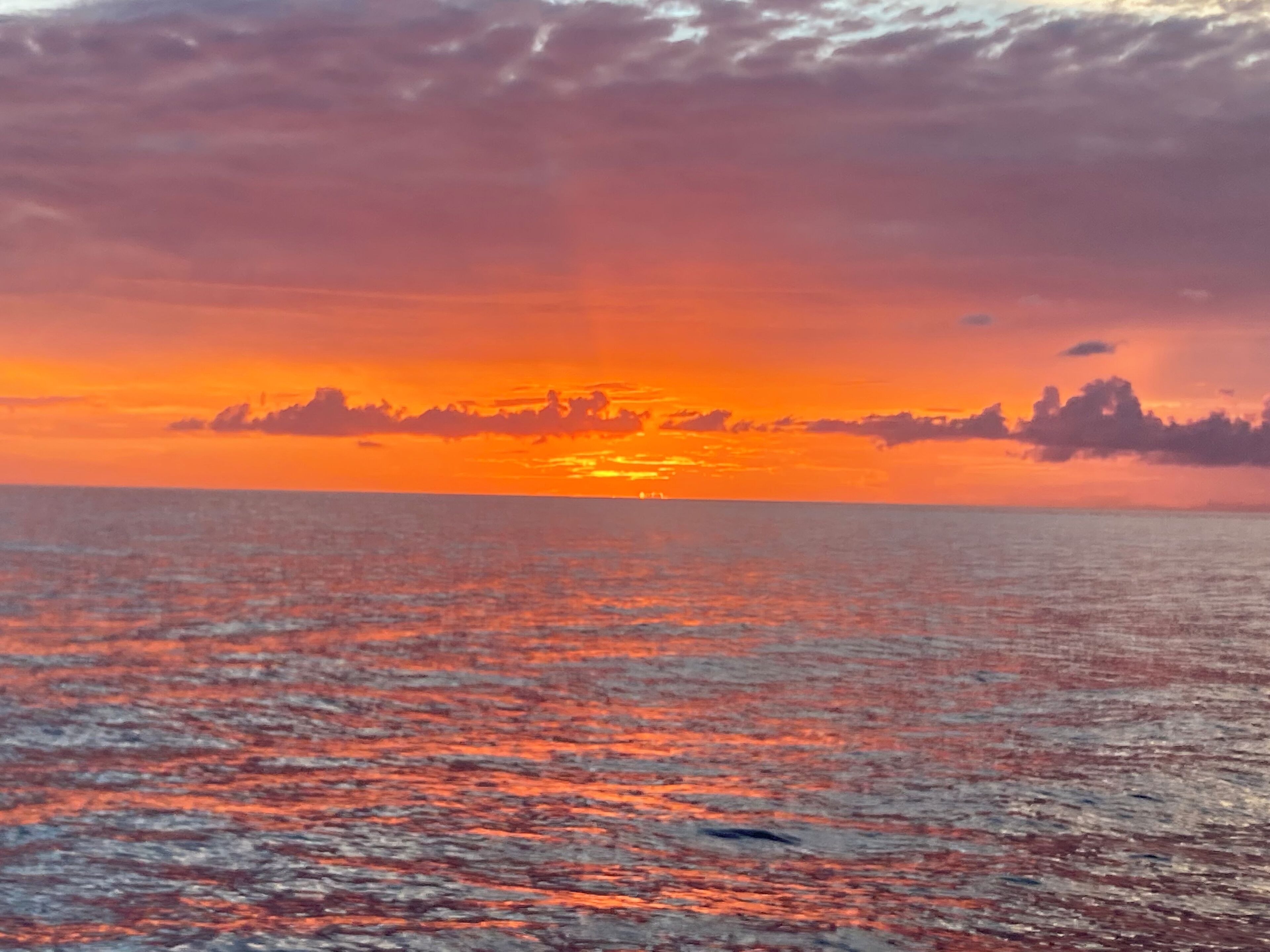 A sunset over a calm sea with a clear horizon.